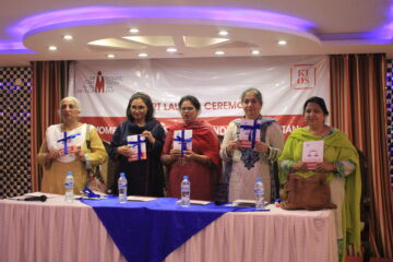 Women on stage holding a booklet