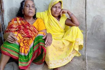 Two women sitting outside a house.